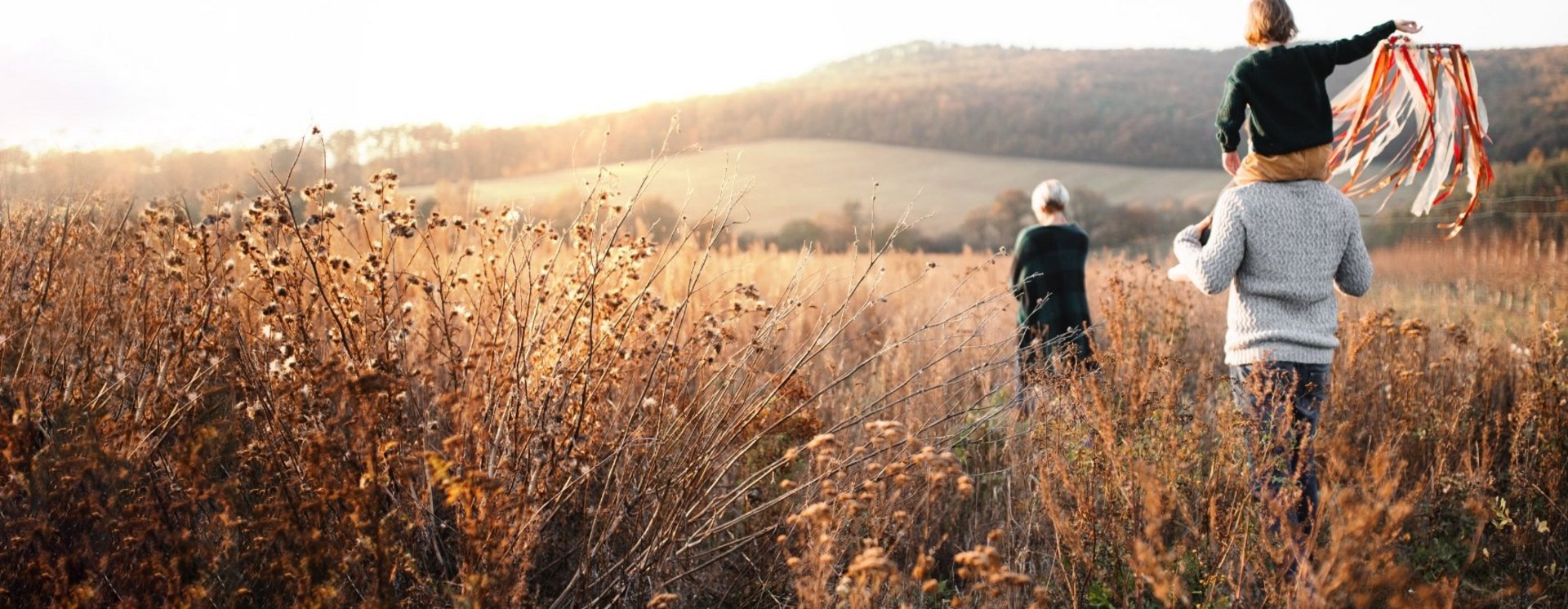 Familie mit Kind spaziert durch sonniges Feld