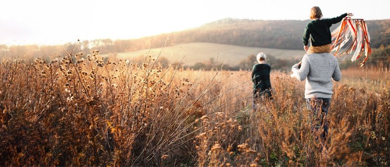 Familie mit Kind spaziert durch sonniges Feld