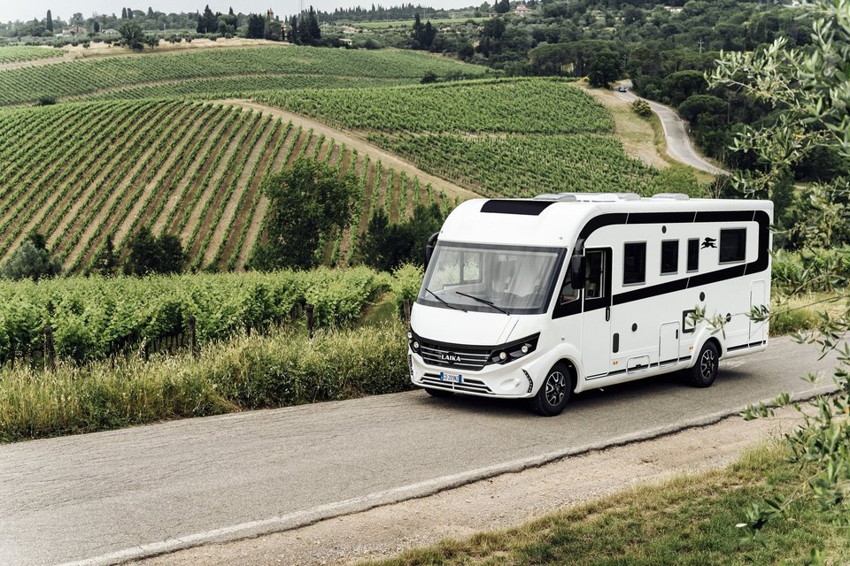 Laika Wohnmobil auf der Straße im grünen Feld 