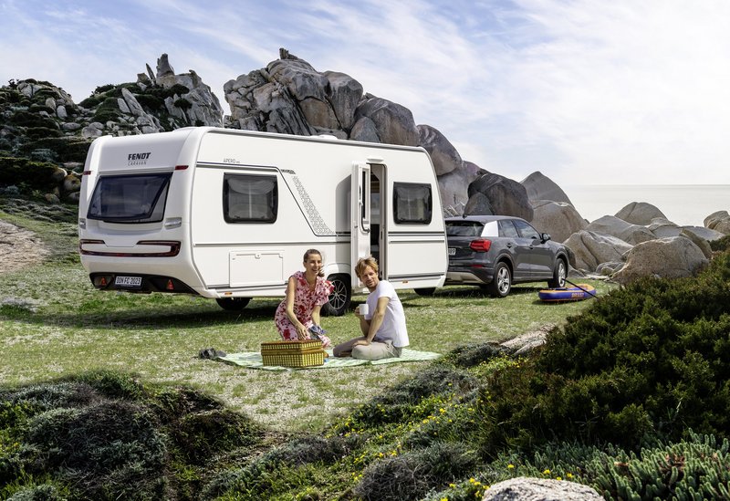 Fendt-Wohnwagen auf einer Wiese mit Personen bei einem Picknick