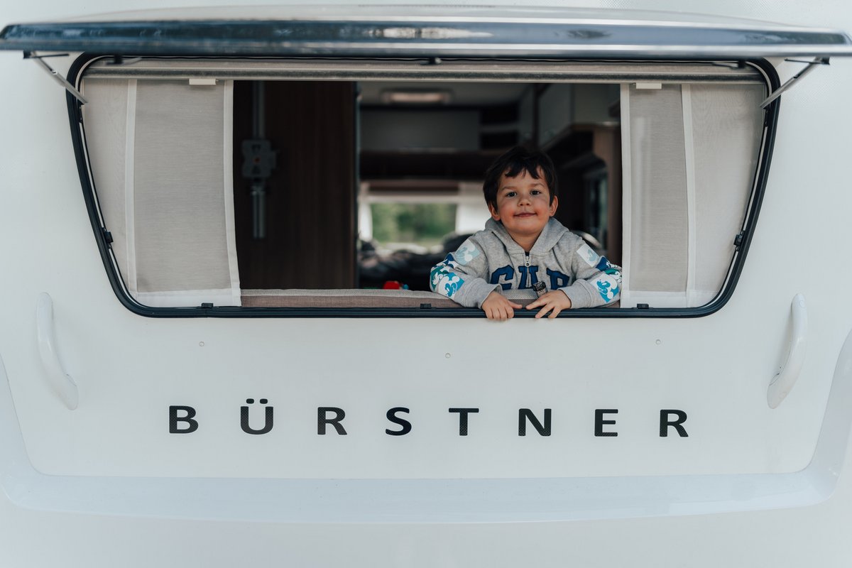 Kleiner Junge schaut aus Bürstner Wohnwagen Fenster