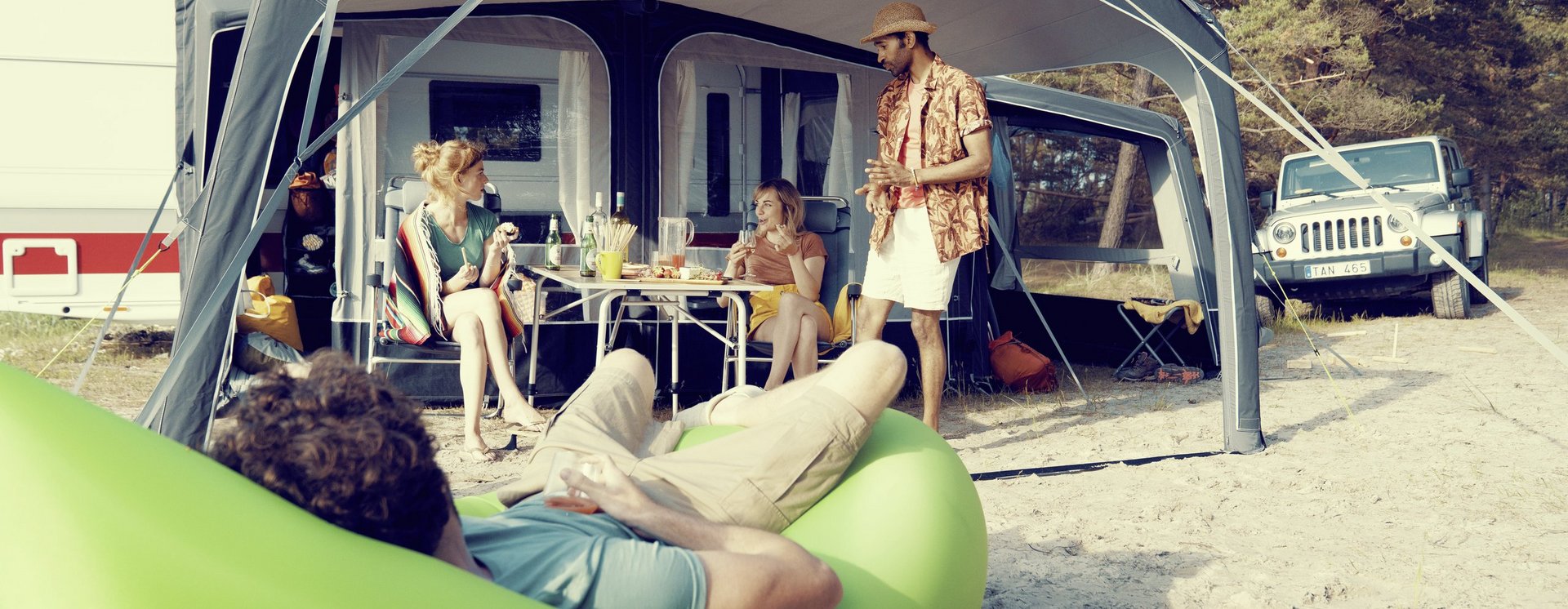 Personen beim Essen unter dem Vorzelt des Wohnwagens am Strand