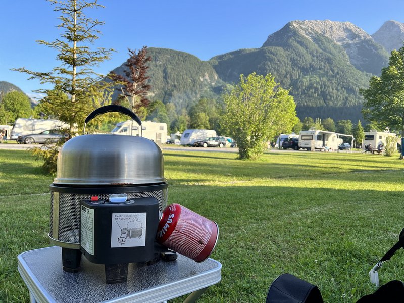 Campingkocher auf grüner Wiese vor Campingplatz