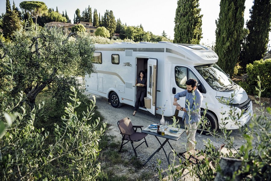 Laika Reisemobil in sonniger Umgebung beim Essen eines Paares 