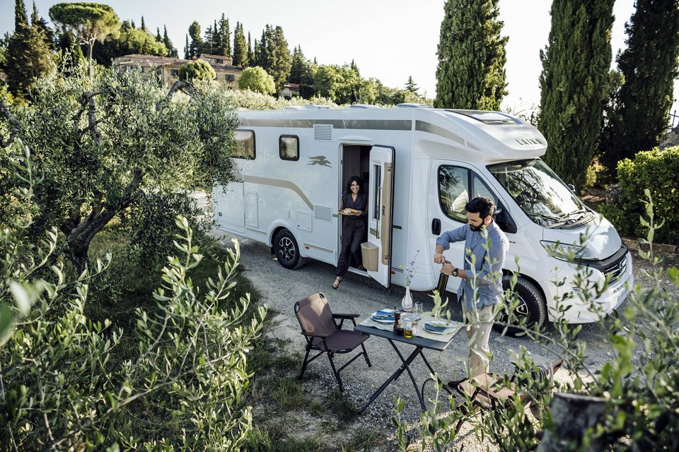 Frau und Mann decken Tisch vor ihrem Campervan