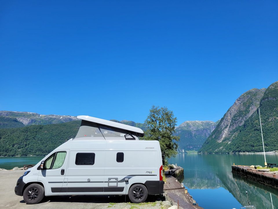 Van neben großem See und Berge im Hintergrund