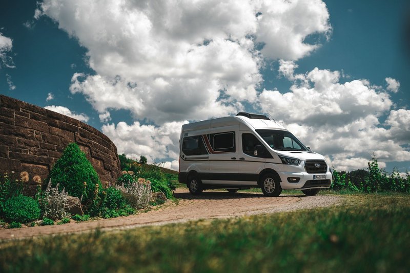 Bürstner Camper Van steht im Grünen neben einer Mauer