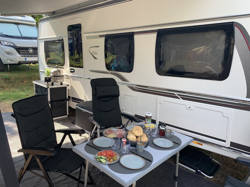 gedeckter Campingtisch vor einem Wohnwagen