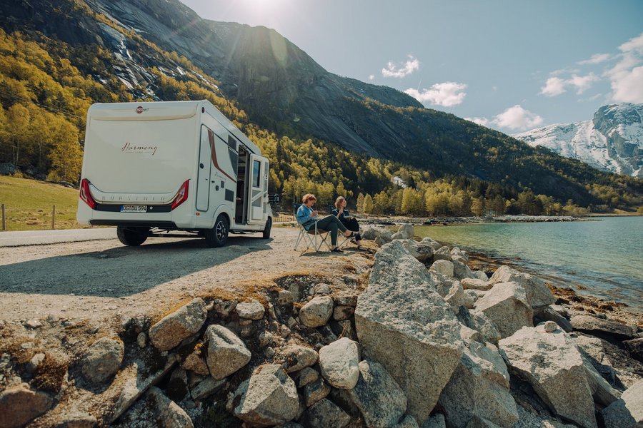 Zwei Frauen auf Campingstühlen neben Bürstner Wohnmobil am See