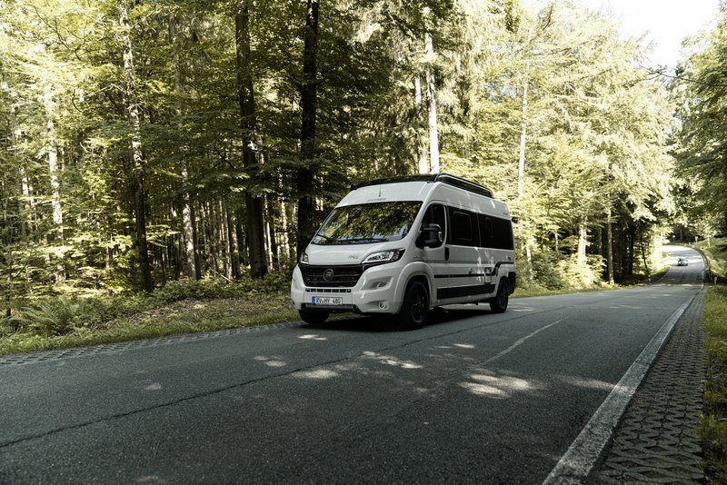 Camper Van auf einer Straße im Wald