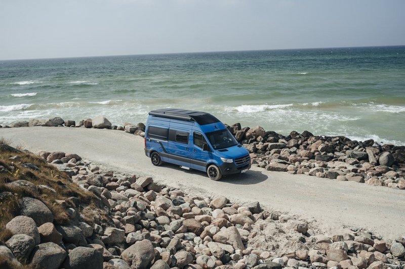 Camper Van fährt auf einer Straße neben dem Meer