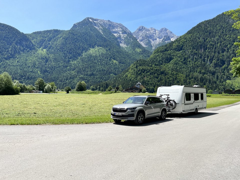 Auto mit Camper vor grüner Berglandschaft