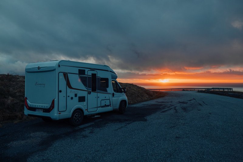 Bürstner Wohnmobil fährt, während im Hintergrund die Sonne über dem Meer untergeht