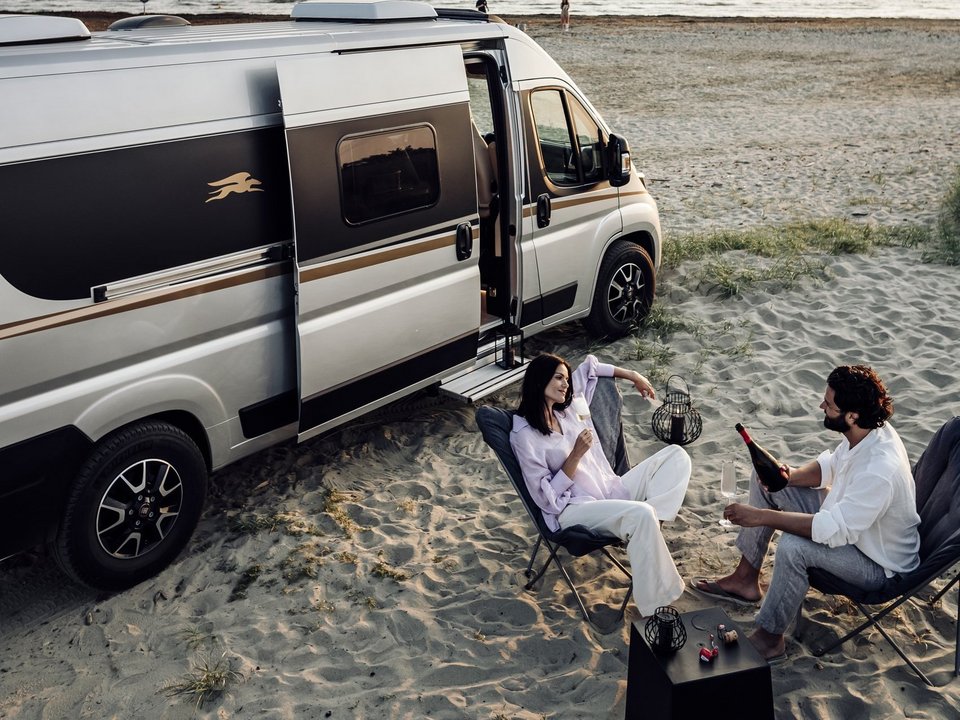 Frau und Mann trinken Wein vor ihrem Campervan