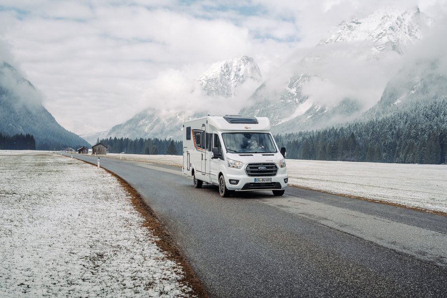 Bürstner Wohnmobil in verschneitem Gebiet, Berge im Hintergrund