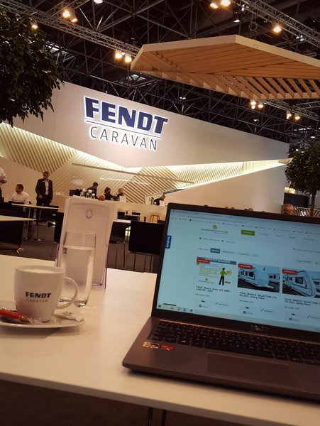 offener Laptop und Kaffeetasse auf einer Messe