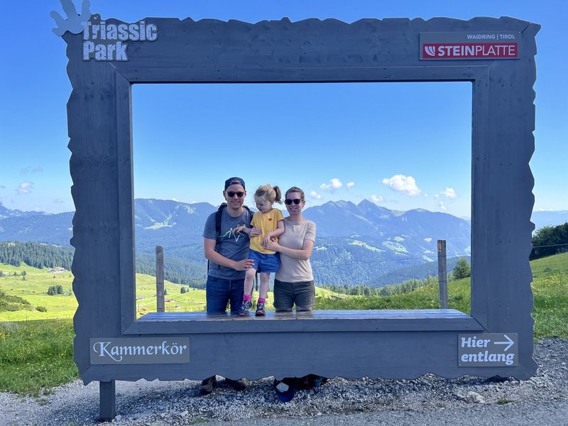 Familie mit Kind in großem Fotorahmen vor grüner Berglandschaft