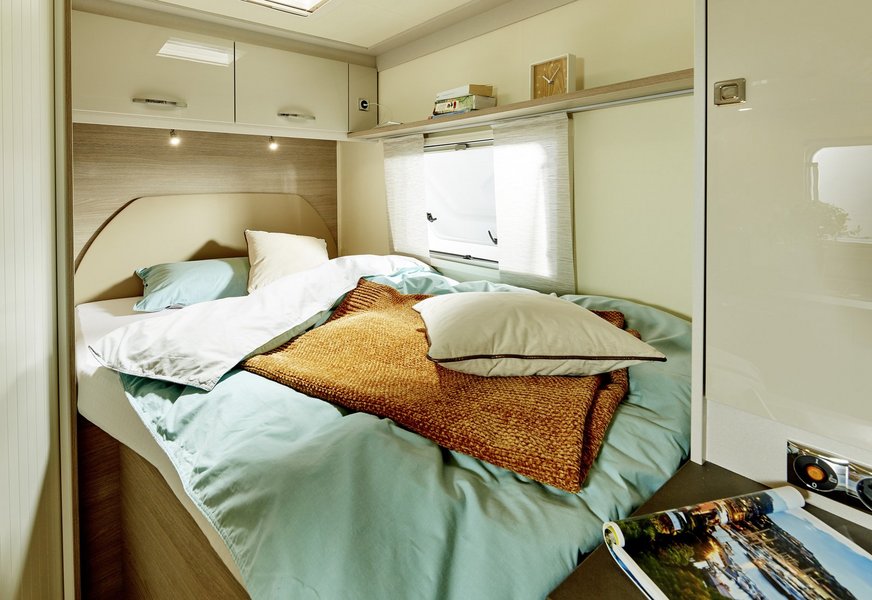 Mit Kissen und Decken bedecktes Bett im Bürstner Wohnmobil