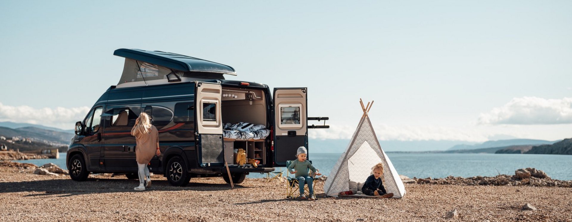 Kinder spielen neben geparktem Bürstner Wohnmobil direkt an einem See