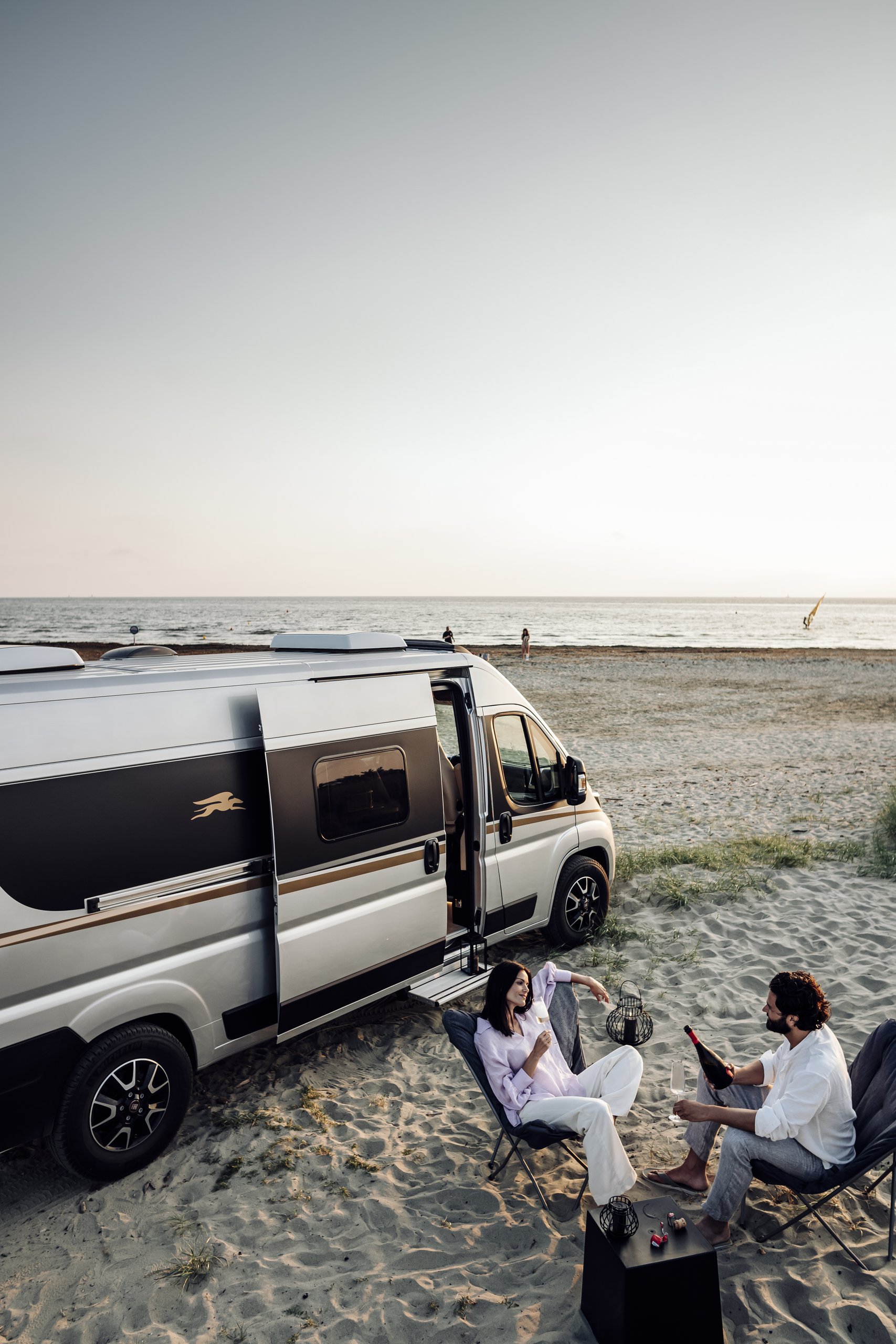Frau und Mann trinken Wein vor ihrem Campervan